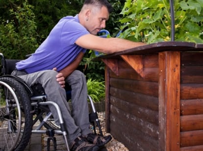A shot of a person on a wheelchair that showcases wheelchair accessible garden beds