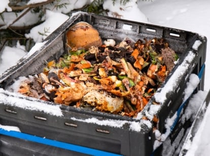 Close-up of an open compost bin filled with bio waste, demonstrating how compost winter methods work in a snow-covered garden.