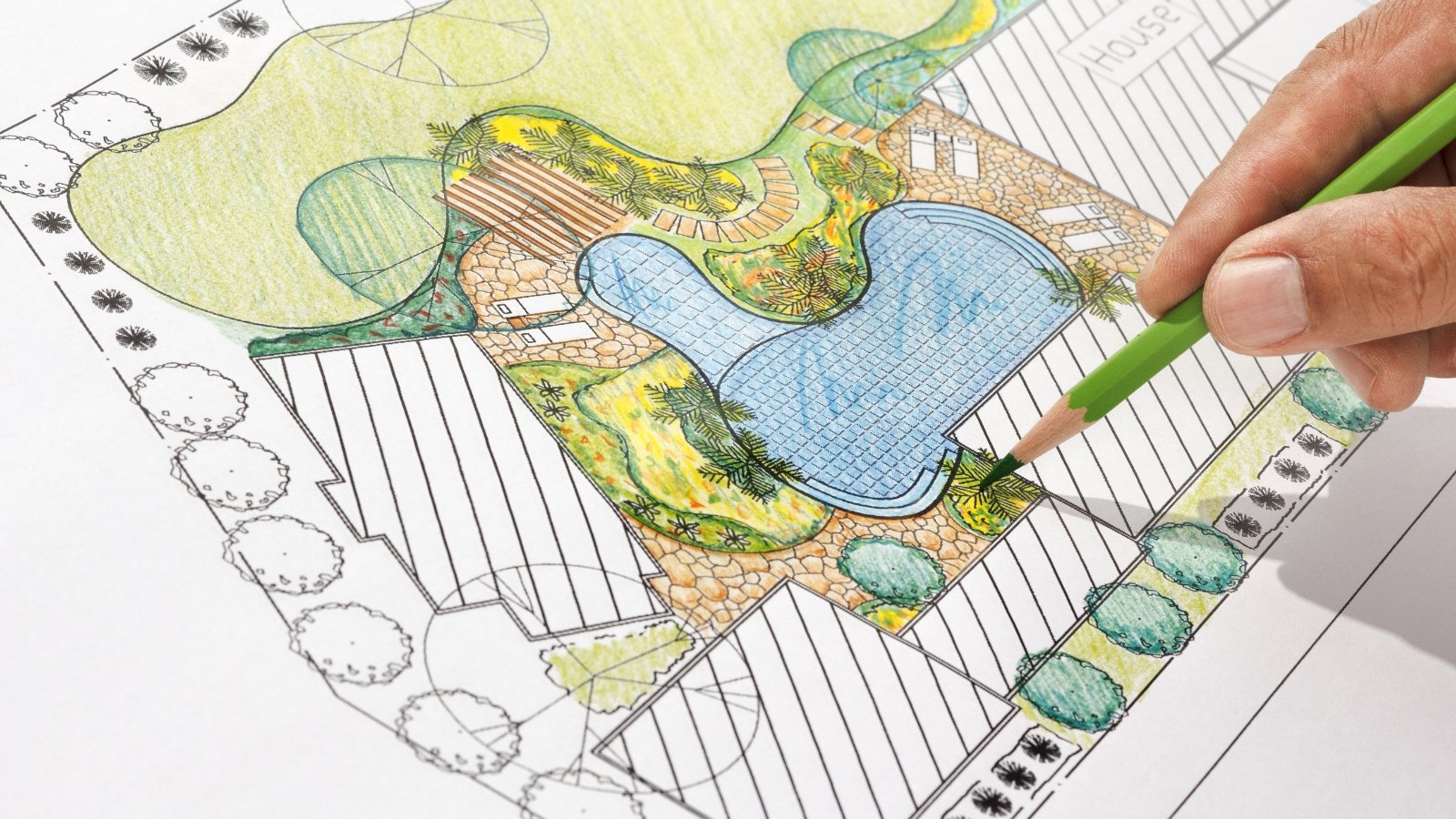 Close-up of a man drawing a landscape architect design backyard plan using a green pencil.