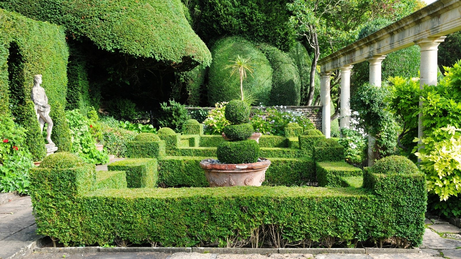 View of the delightful formal garden with manicured box hedges, topiaries, statues, and columns set at the front entrance to the garden.
