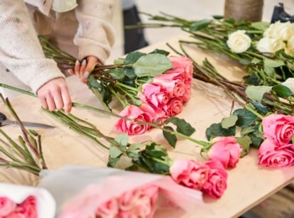 A florist sorts a bouquet of delicate pink roses on a wooden table to regrow roses from the bouquet.